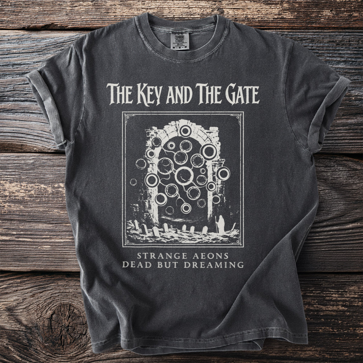 Dark gray t-shirt with white text and graphic: "The Key and The Gate" and "Strange Aeons Dead But Dreaming".