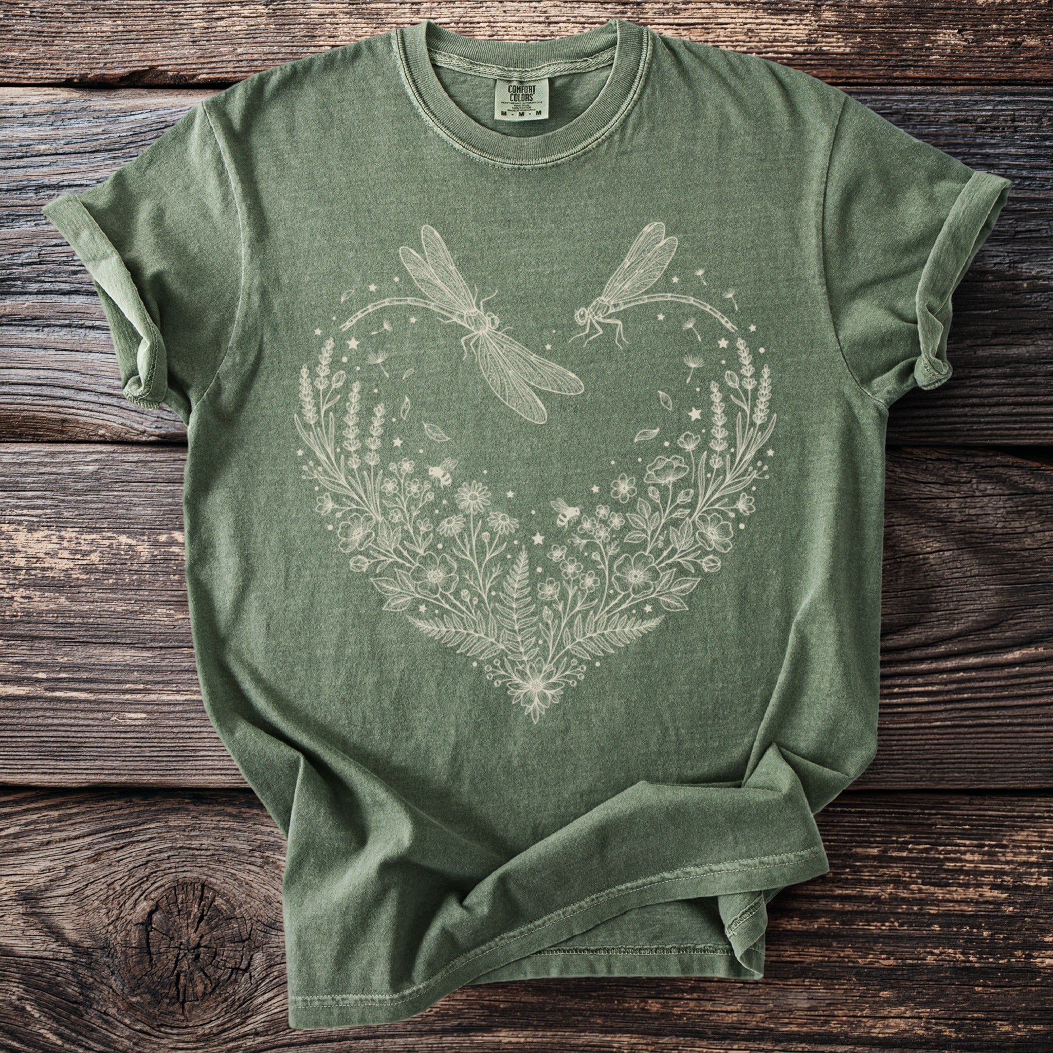 Green t-shirt with a white linework design of dragonflies and a floral heart.