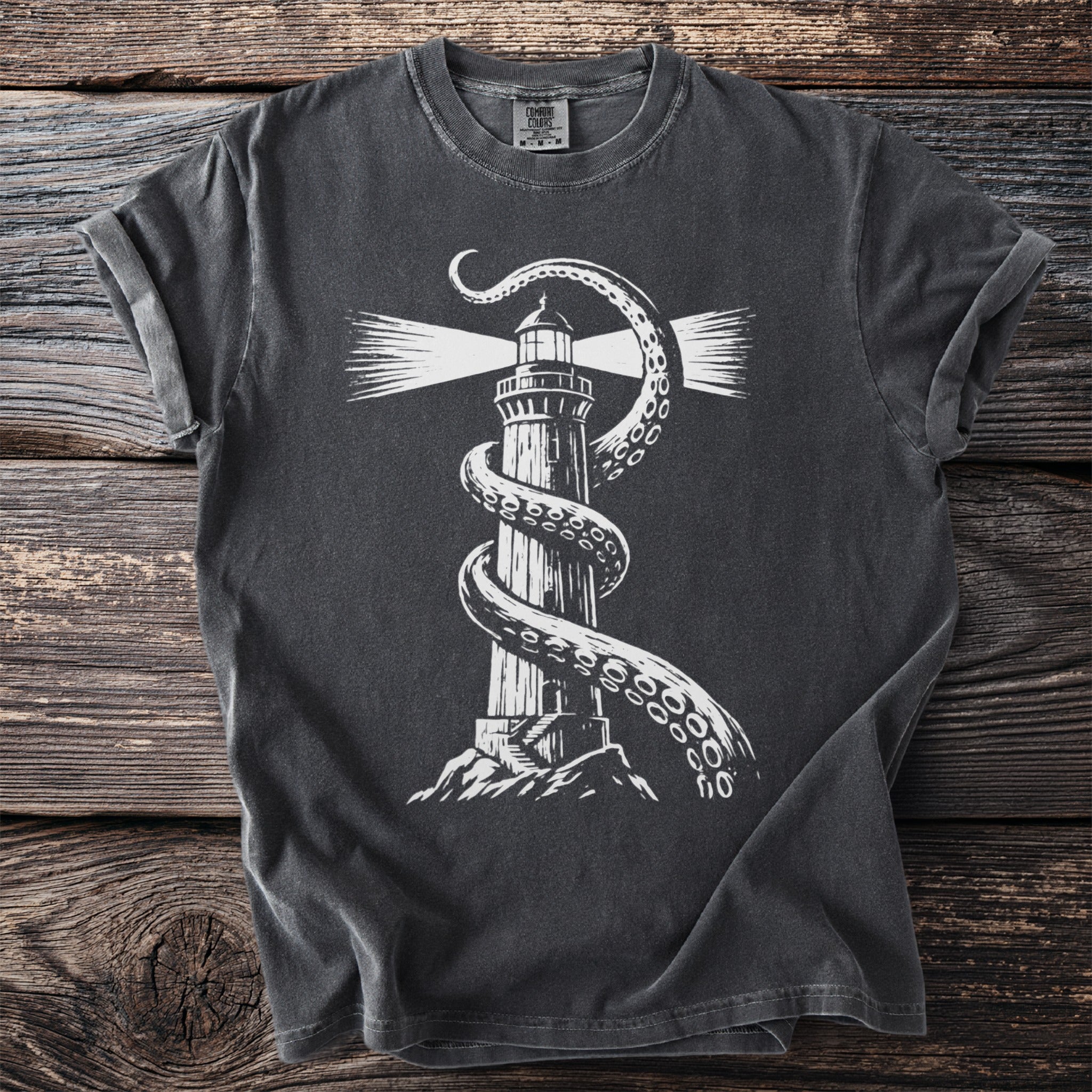 Dark t-shirt with white print of a lighthouse wrapped by kraken tentacles.