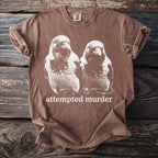 Brown t-shirt with white graphic of two birds and text "attempted murder".