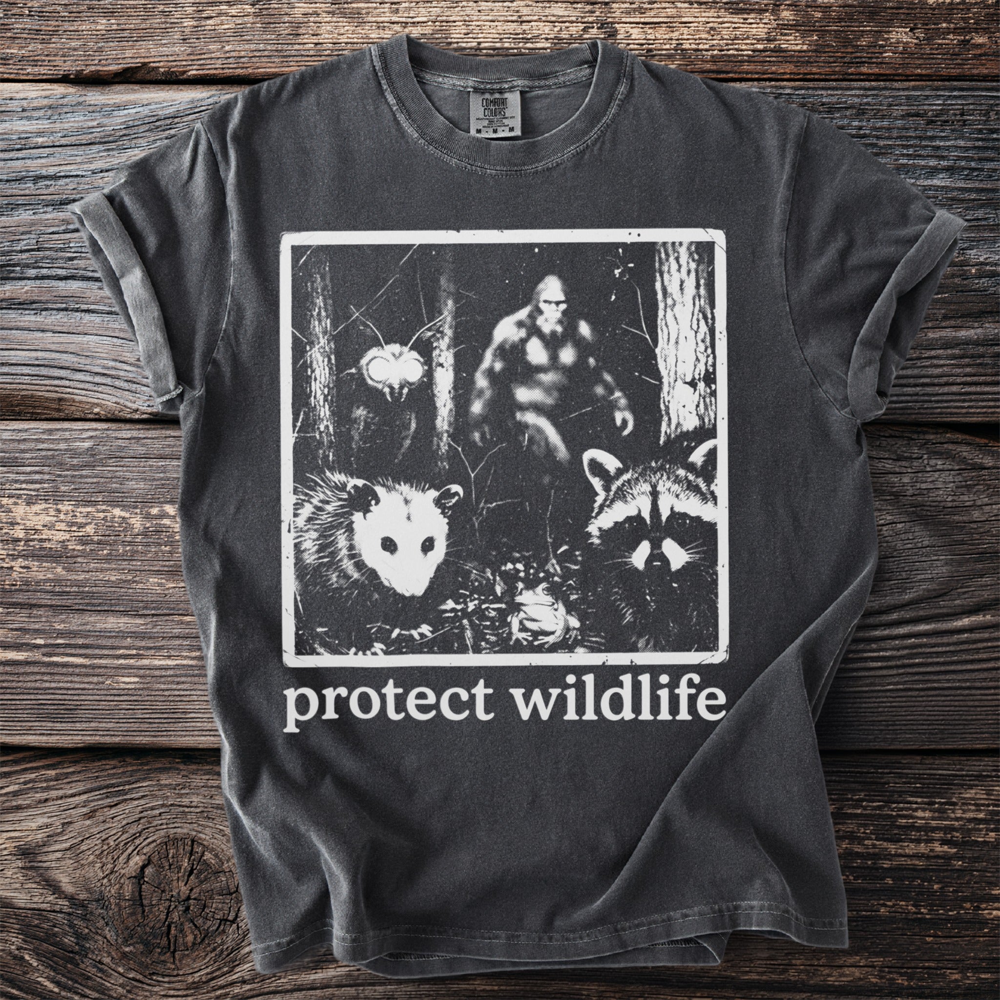 Charcoal t-shirt with graphic of Bigfoot, possum, raccoon, and moth with "protect wildlife" text.