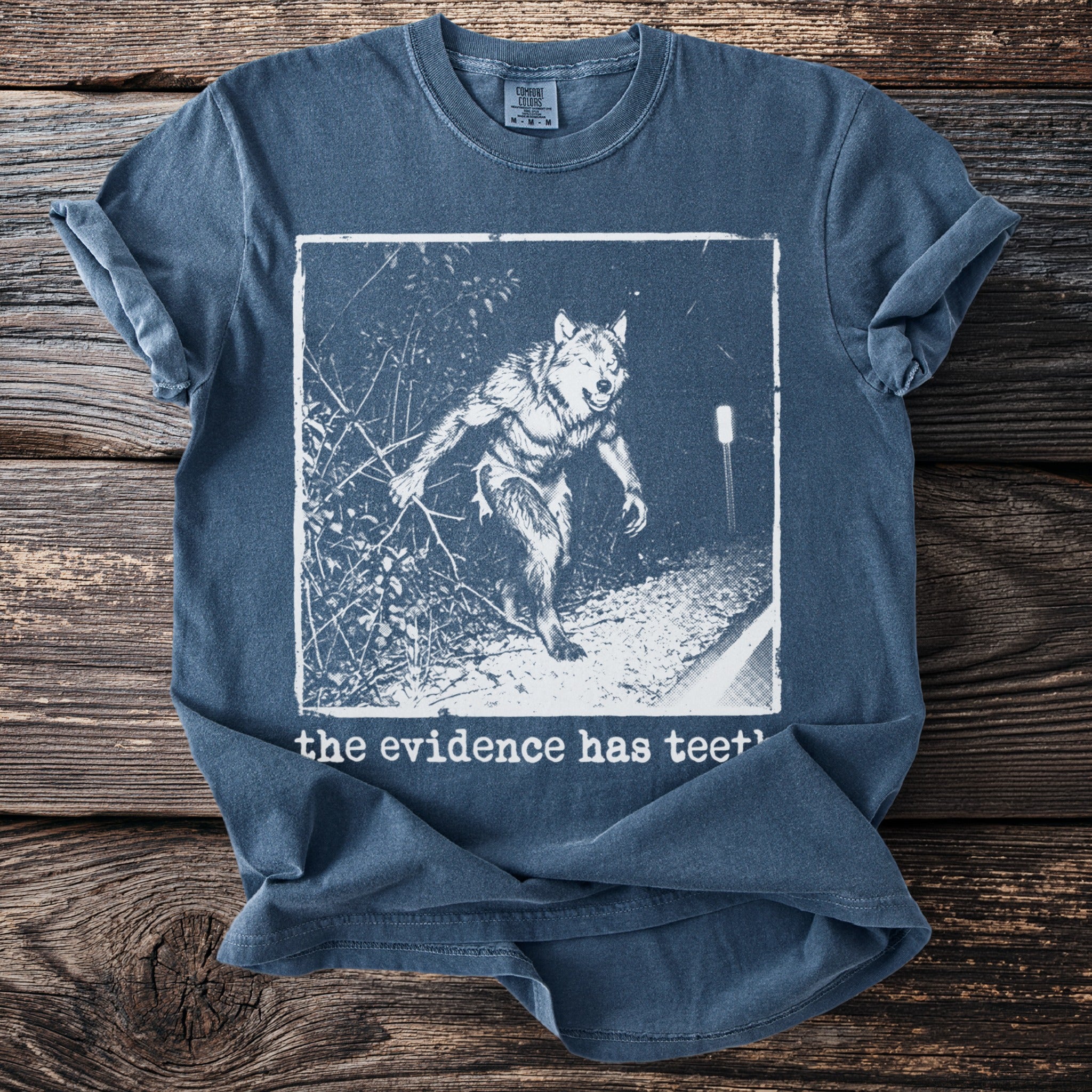 Blue t-shirt with werewolf graphic and "the evidence has teeth" text.