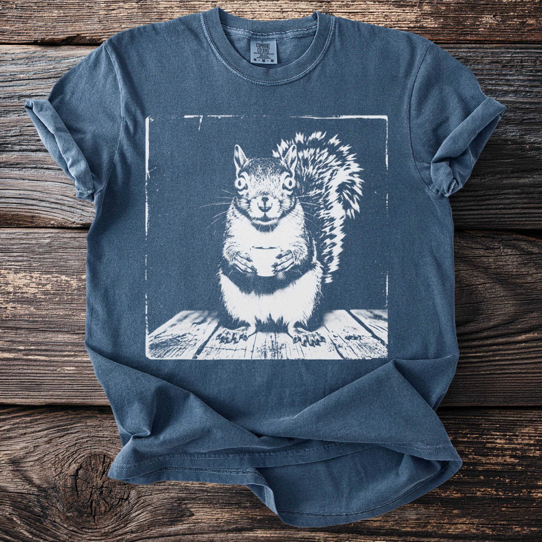 Slate blue t-shirt with a white graphic of a squirrel holding a coffee cup.