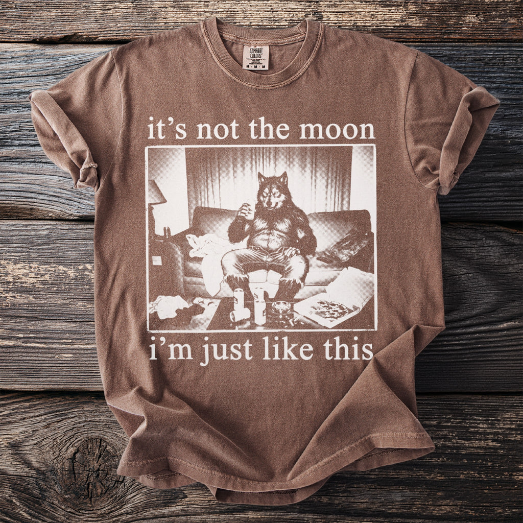 Brown t-shirt with a graphic of a werewolf sitting on a couch with drinks and pizza.