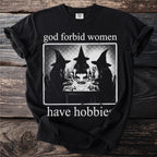 Black t-shirt with "god forbid women have hobbies" and image of three witches at a table.