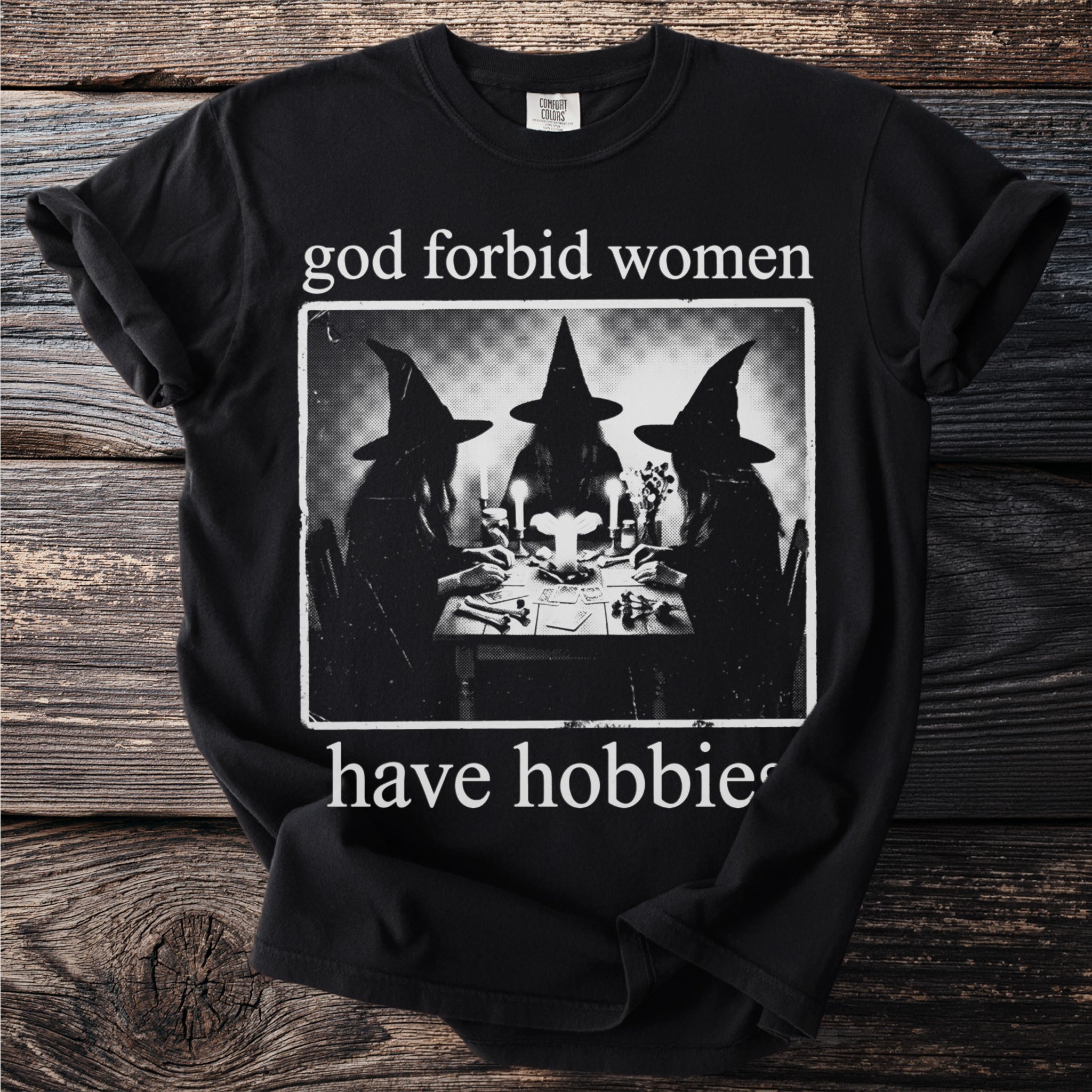 Black t-shirt with "god forbid women have hobbies" and image of three witches at a table.