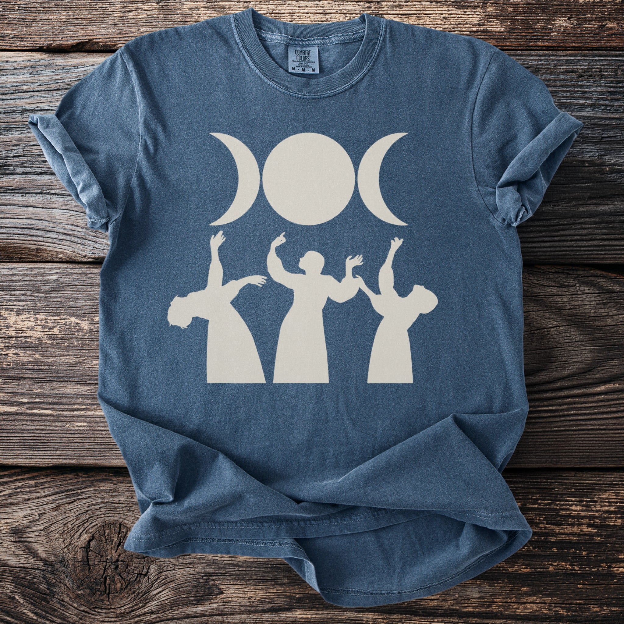 Blue t-shirt with triple moon and three figures dancing graphic print.