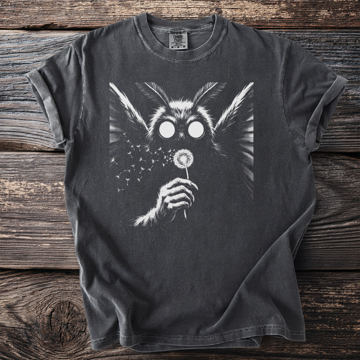 Dark t-shirt with graphic of moth-like creature blowing dandelion seeds.