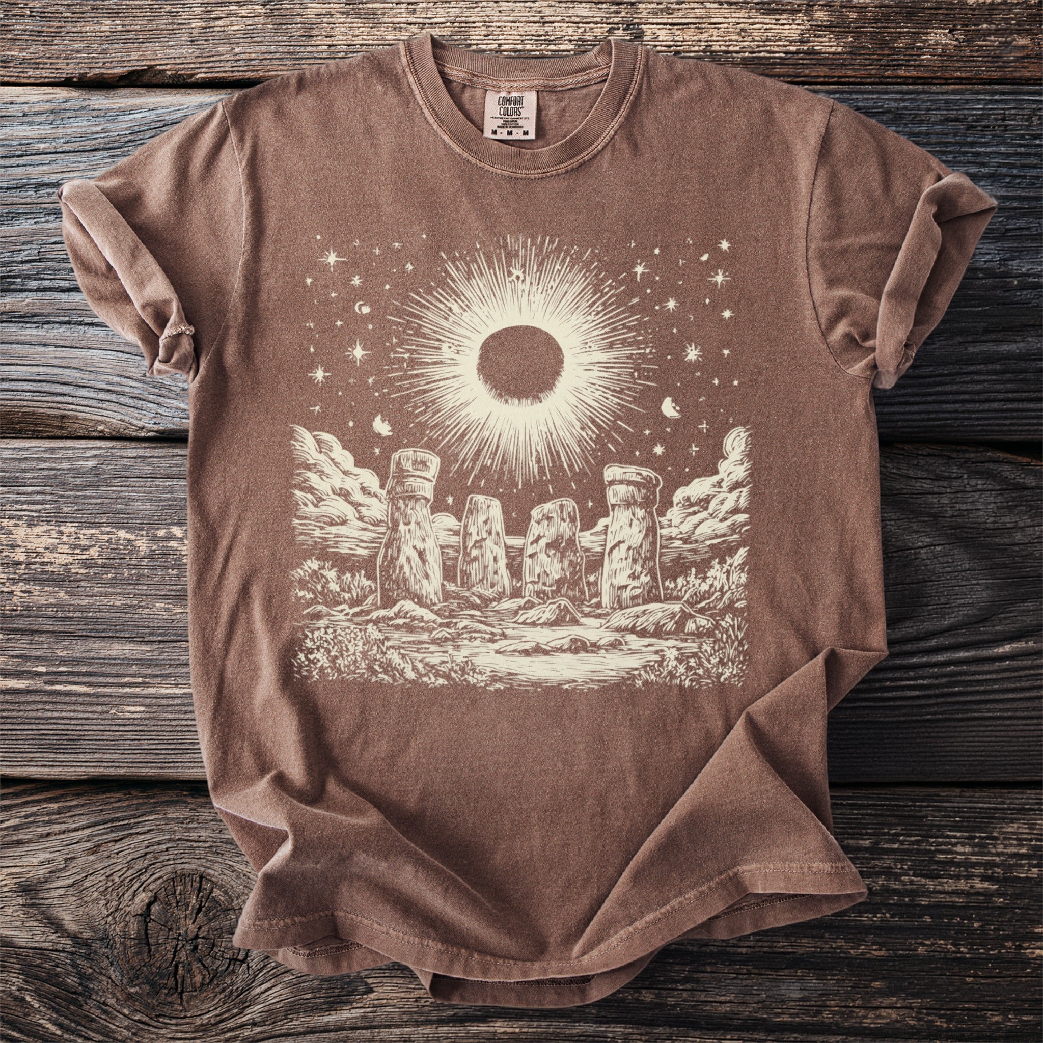Brown t-shirt with a celestial Stonehenge graphic and "Comfort Colors" tag.