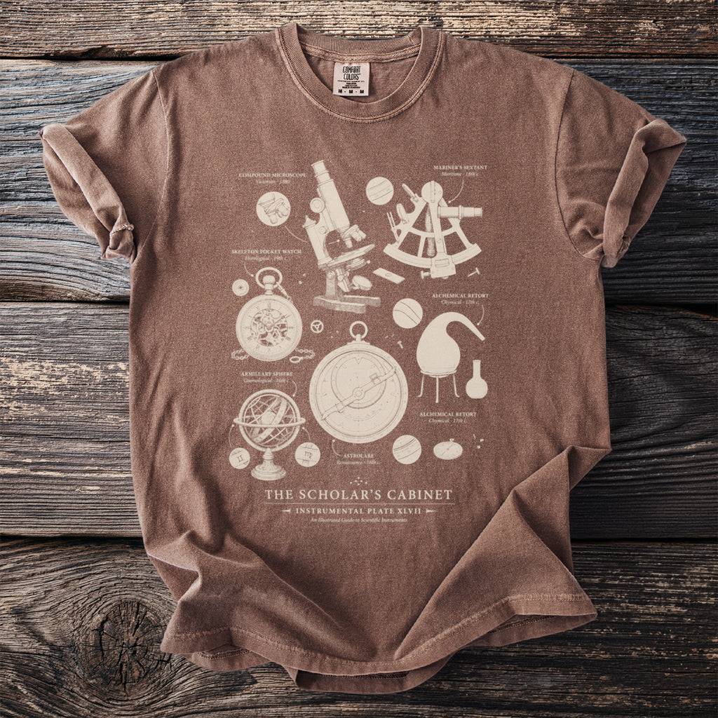 Brown t-shirt printed with "The Scholar's Cabinet" design featuring scientific instruments.