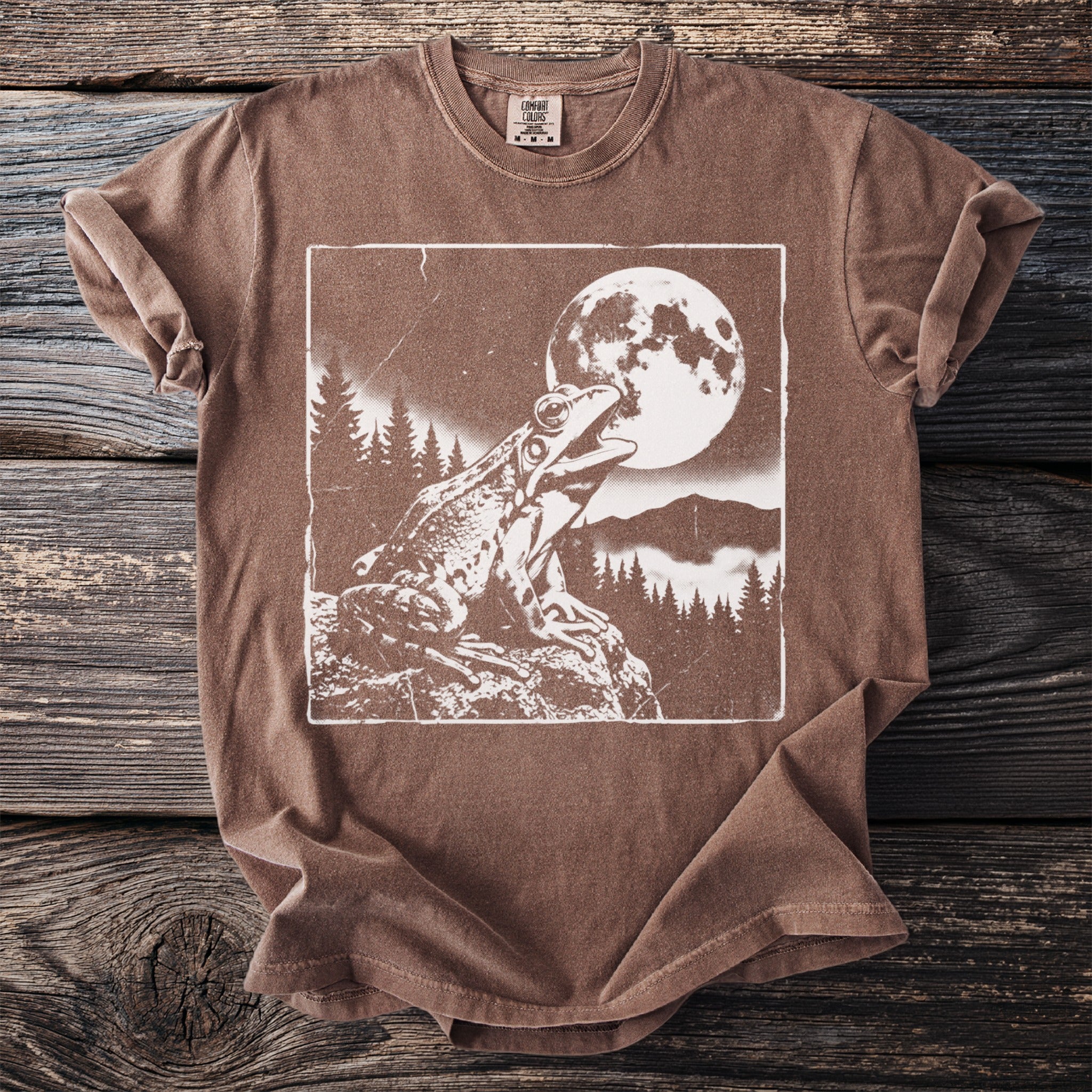 Brown t-shirt with white graphic of a frog under a full moon with trees.