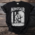 Black t-shirt with white text "MINOTAUR" and illustration of a minotaur in a stone labyrinth.