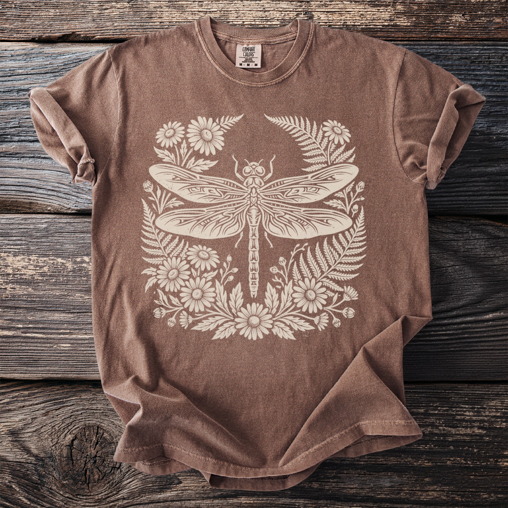 Brown t-shirt with a cream-colored dragonfly and floral graphic.