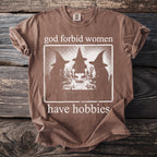 Brown t-shirt with "god forbid women have hobbies" and a vintage witch graphic.