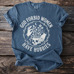 Blue t-shirt with white text "GOD FORBID WOMEN HAVE HOBBIES" and skull graphic.