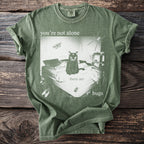 Green t-shirt with print: cat on bed, spider, moth, flies, and text "you're not alone there are bugs".