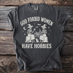 Dark gray t-shirt with "God Forbid Women Have Hobbies" text and skeleton graphics.
