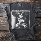 T-shirt with "nocturnal by necessity" text and a black and white graphic of a wolf feeding a kitten.