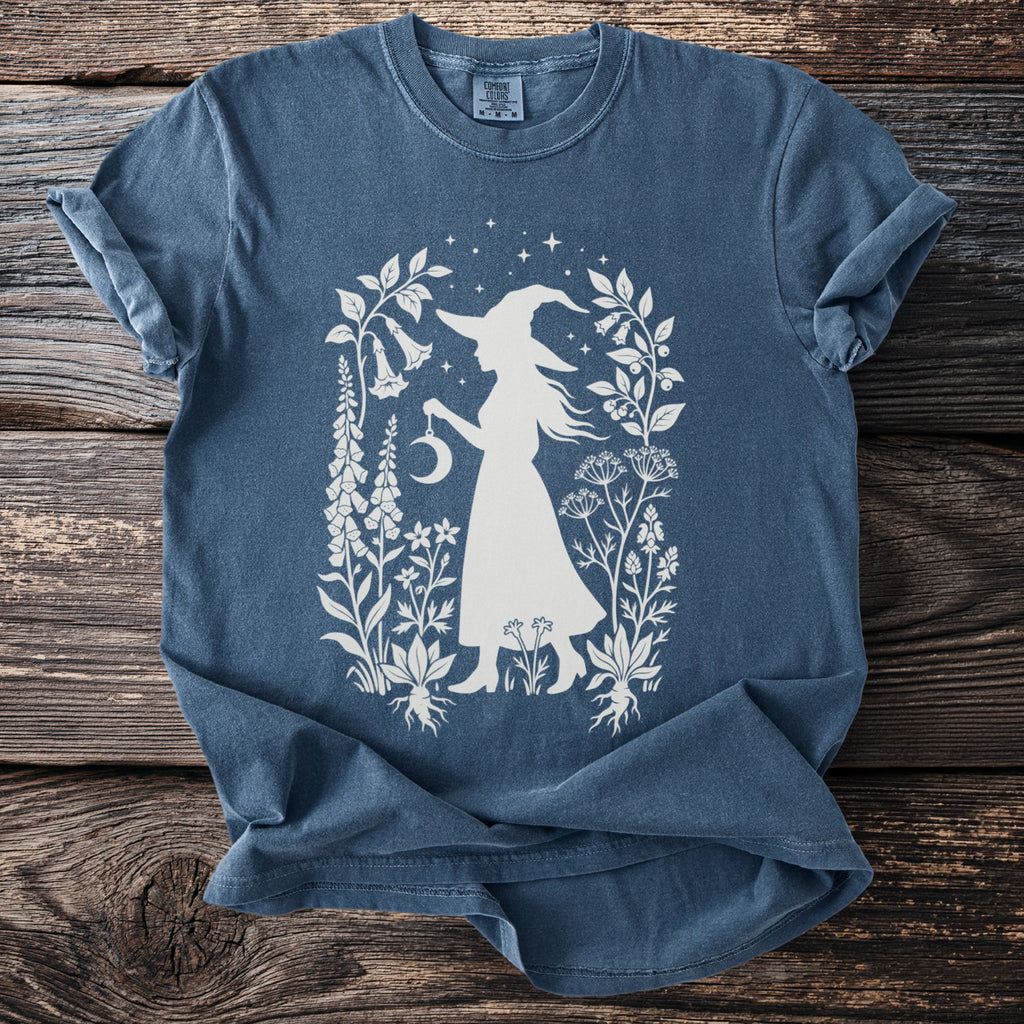 Blue t-shirt with white witch silhouette and botanical design.