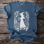 Blue t-shirt with white witch silhouette and botanical design.