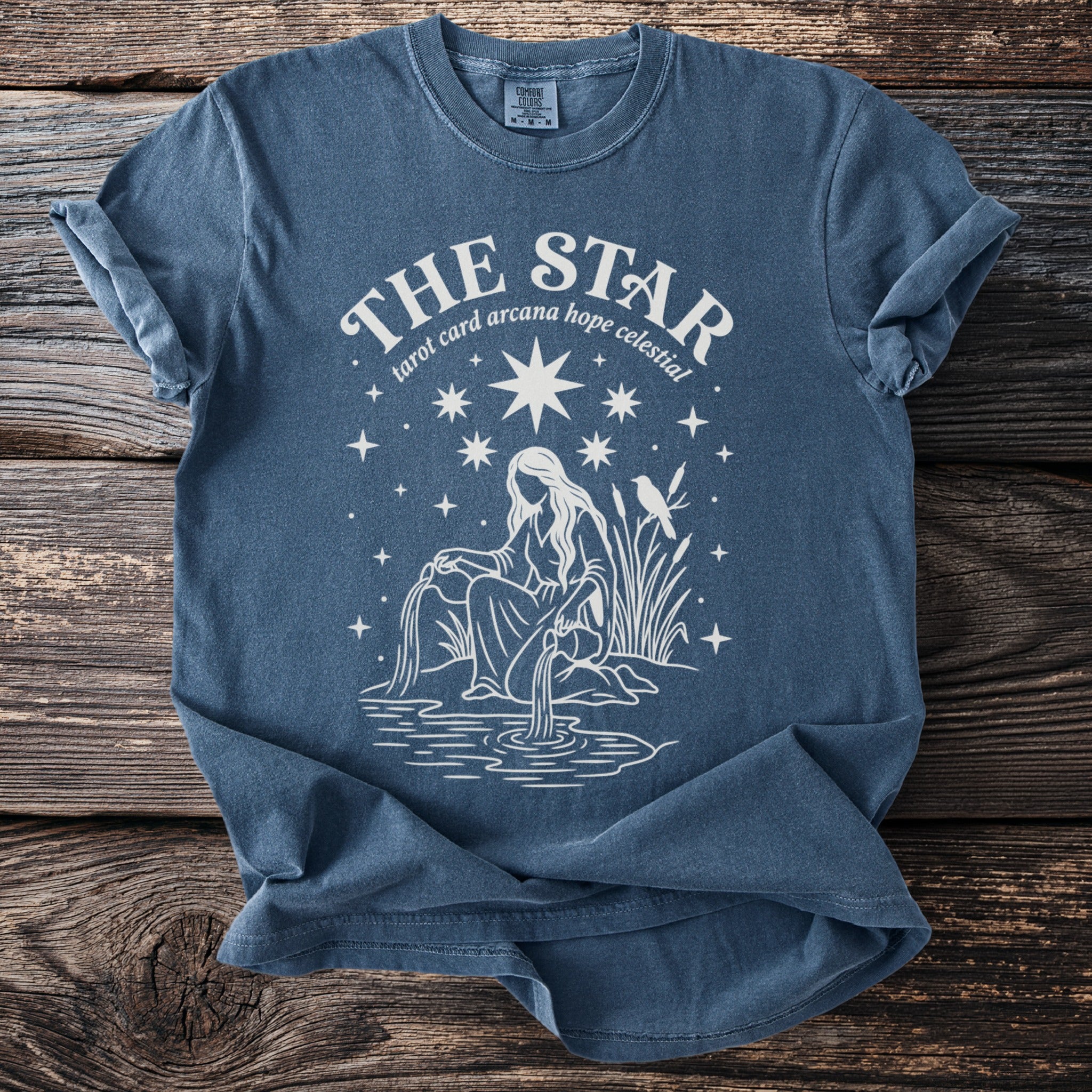 Blue t-shirt with white graphic of "The Star" tarot card and celestial elements.