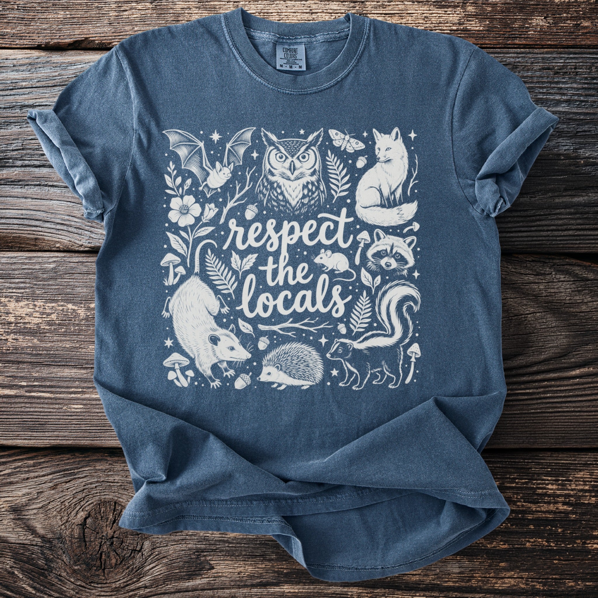 Blue t-shirt with "respect the locals" text and forest animals illustration.