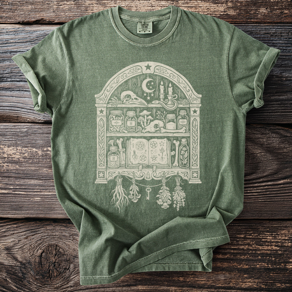 Green t-shirt with a cream-colored occult bookshelf graphic.