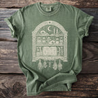 Green t-shirt with a cream-colored occult bookshelf graphic.