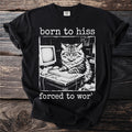 Black t-shirt with a vintage illustration of an angry cat at a desk with a computer and keyboard. Text reads "born to hiss forced to wor'".