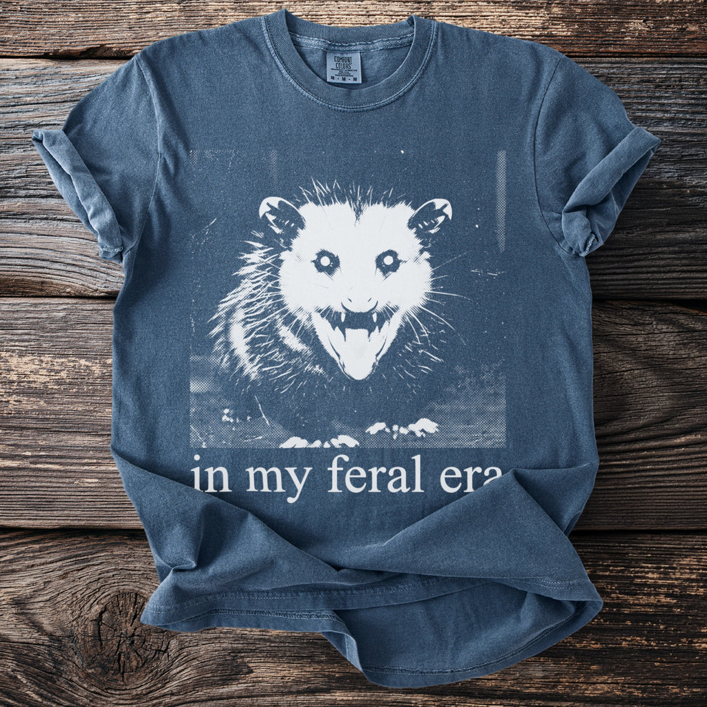 Blue t-shirt with opossum graphic and "in my feral era" text.