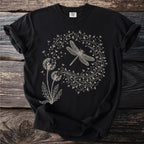 Black t-shirt with a white line drawing of a dragonfly surrounded by dandelions and hearts.