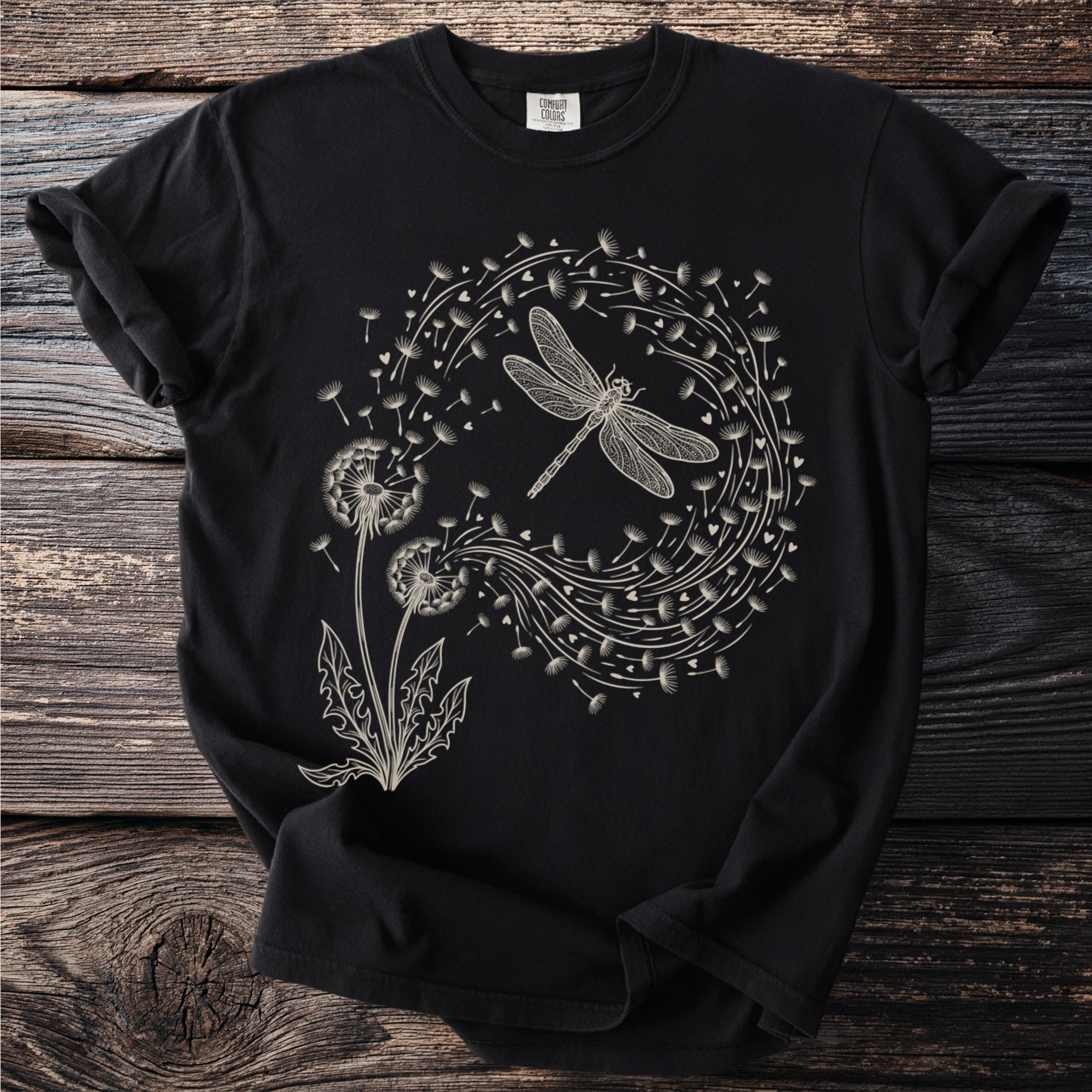 Black t-shirt with a white line drawing of a dragonfly surrounded by dandelions and hearts.