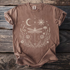 Brown t-shirt with a white line art design of a dragonfly and celestial elements.