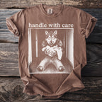 Brown t-shirt with graphic of wolf in jeans holding a baby and text "handle with care".
