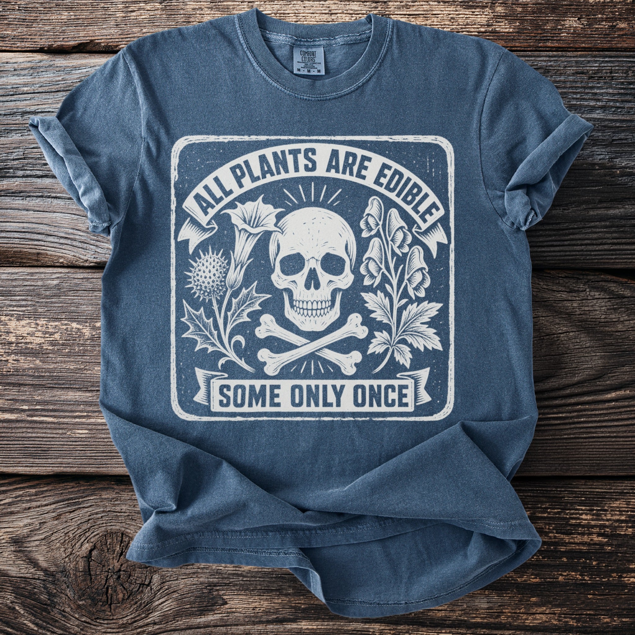 Blue t-shirt with skull, crossbones, and text "All Plants Are Edible Some Only Once".