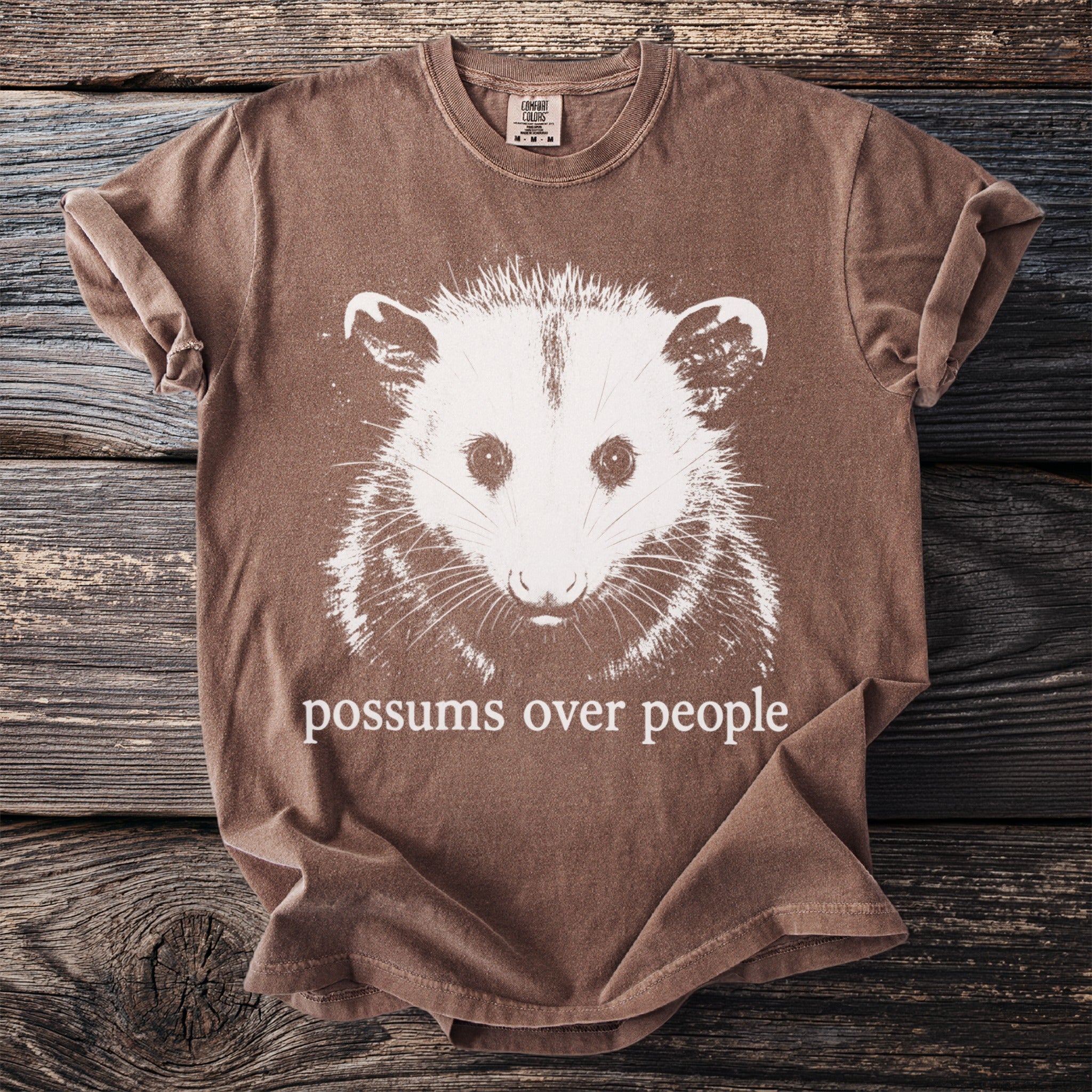 Brown comfort colors t-shirt with white possum graphic and text.