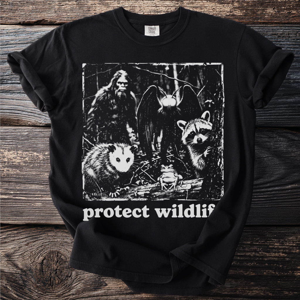 Black t-shirt with Bigfoot, bat, opossum, raccoon, and frog graphic with text "protect wildlif".