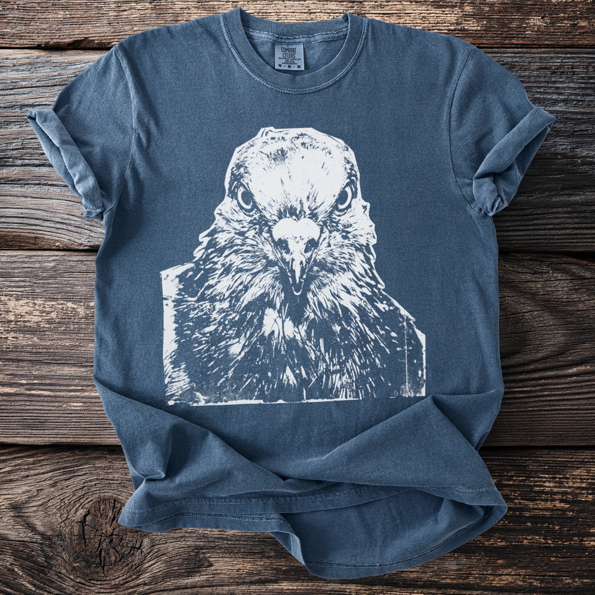 Indigo t-shirt with white graphic of an intense pigeon's face and Comfort Colors tag.
