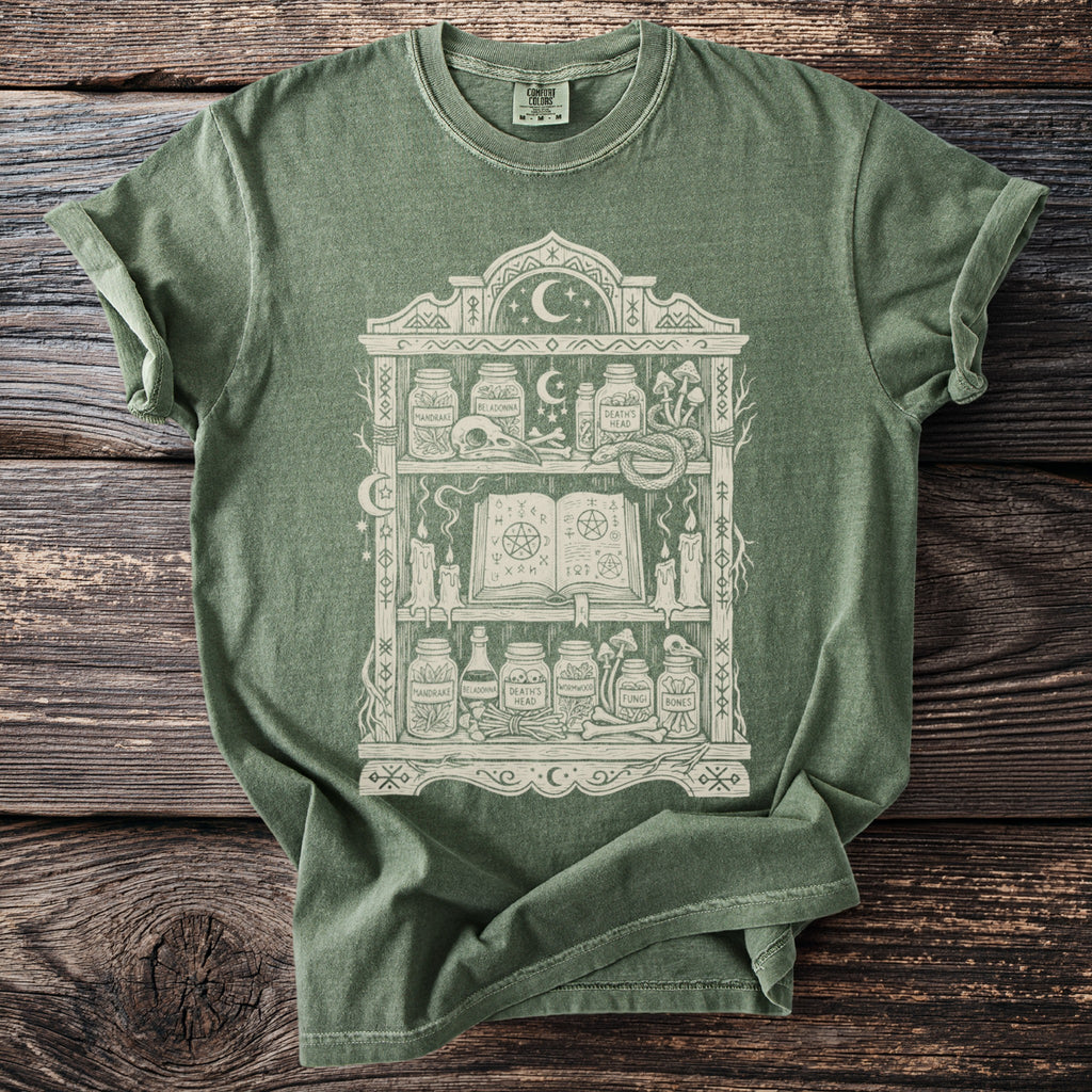 Green t-shirt with mystical apothecary shelf graphic and Comfort Colors tag.