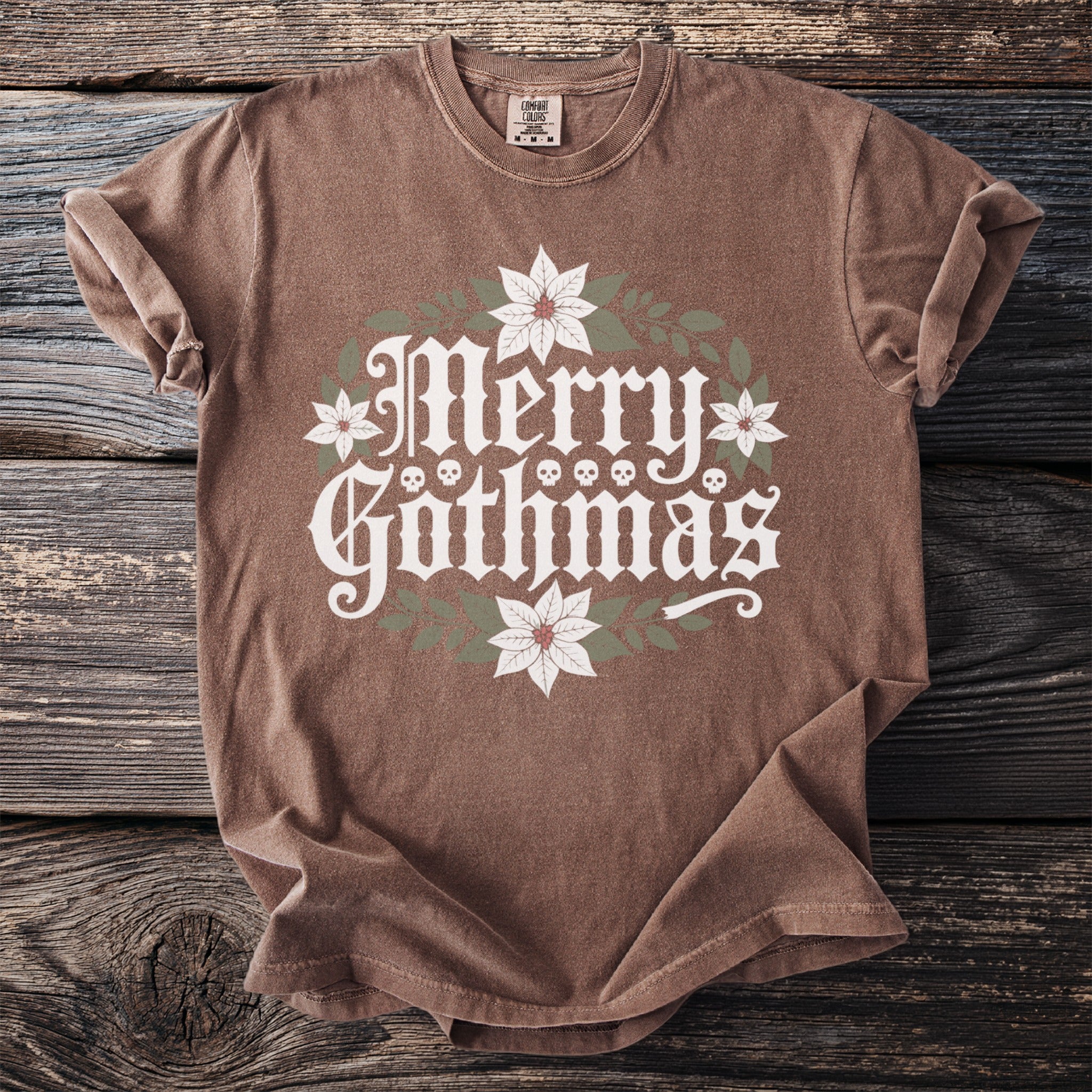 Brown t-shirt with "Merry Gothmas" graphic with skulls and poinsettias.