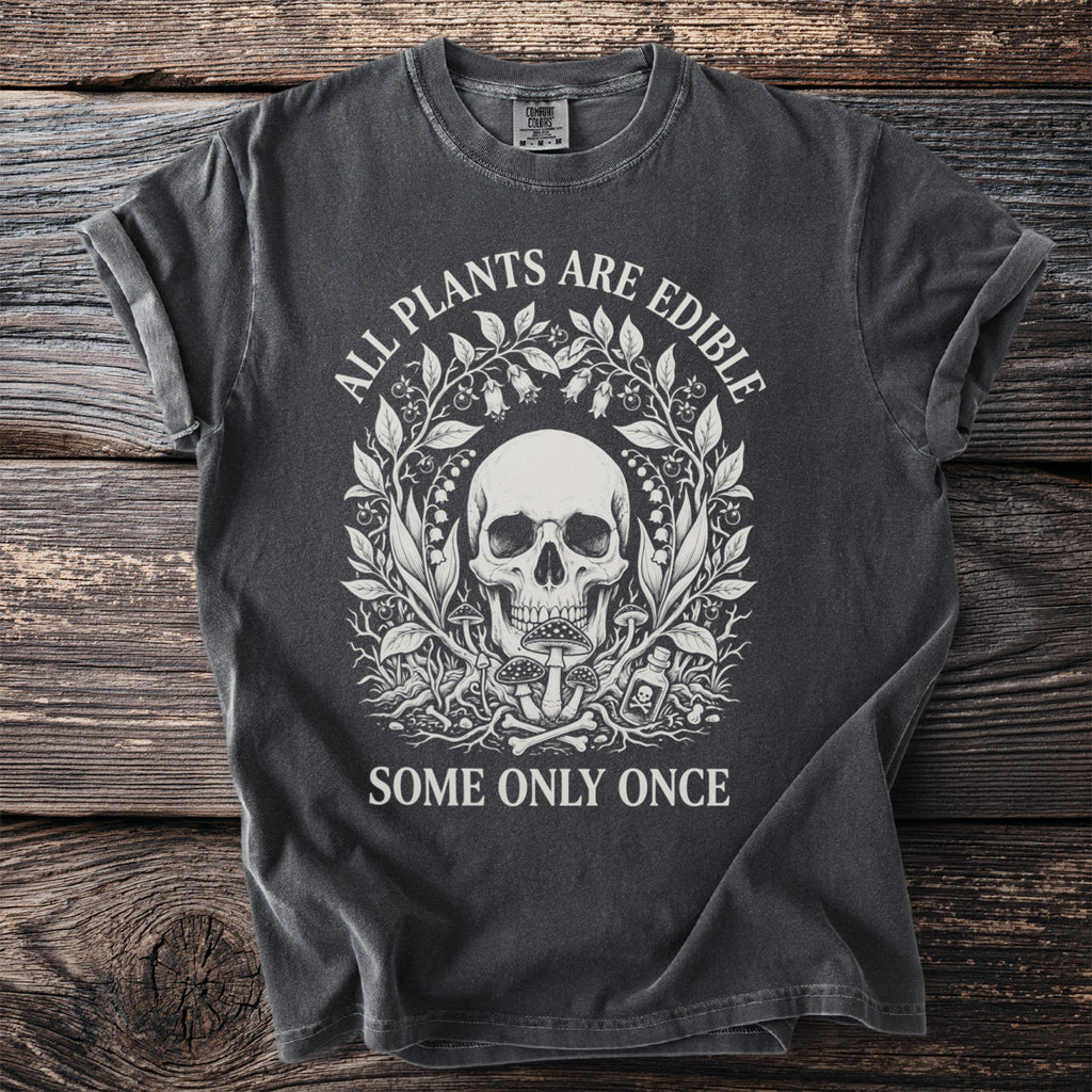 Dark t-shirt with a skull and botanical design, saying "ALL PLANTS ARE EDIBLE SOME ONLY ONCE".