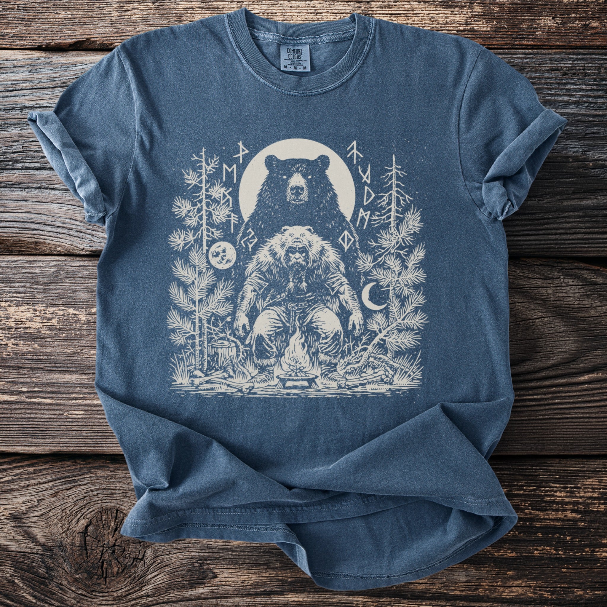 Blue t-shirt with graphic of a bear, a man in furs, and runes around a campfire.