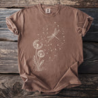 Brown t-shirt with a white dandelion and dragonfly graphic and Comfort Colors tag.