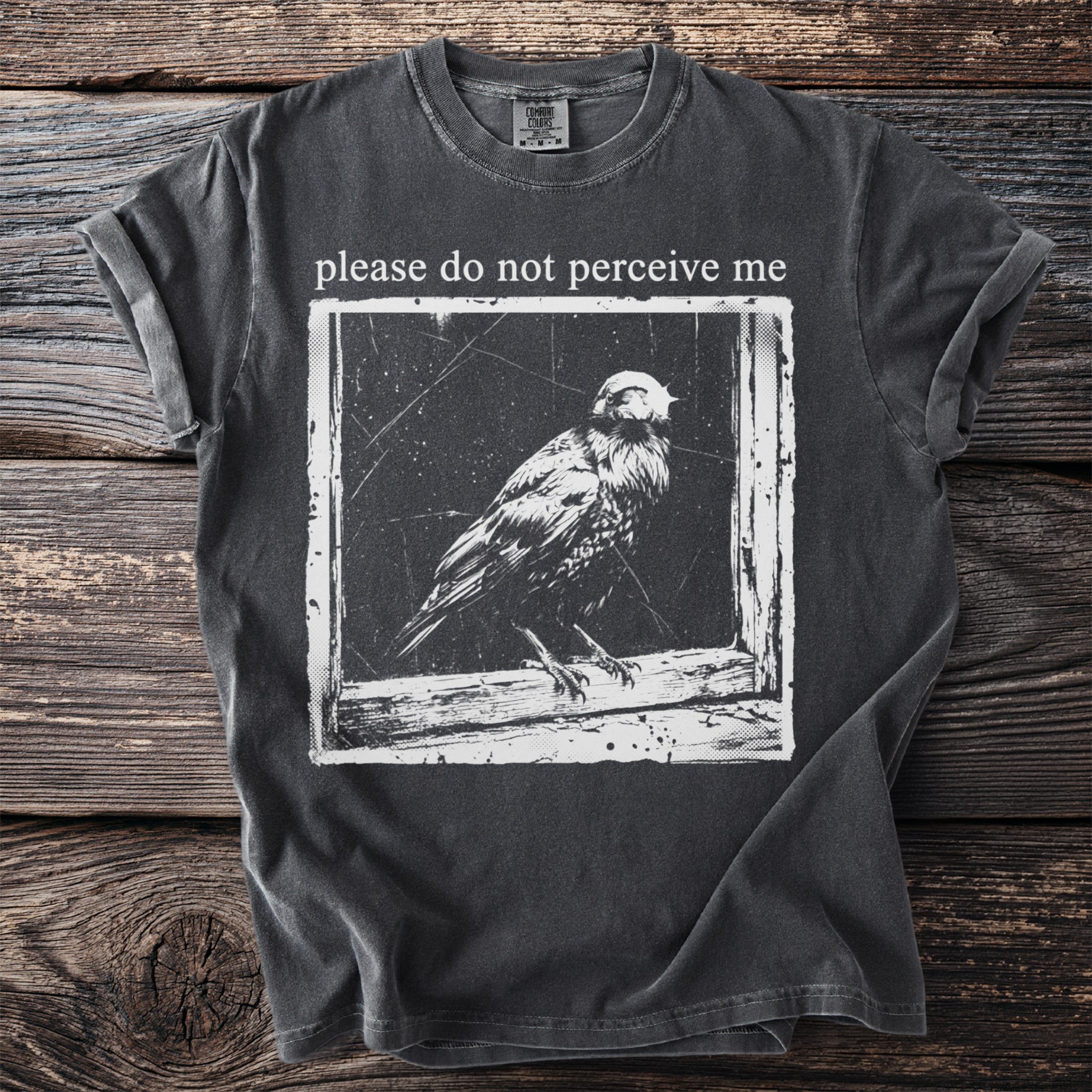 T-shirt with text "please do not perceive me" and a bird graphic.