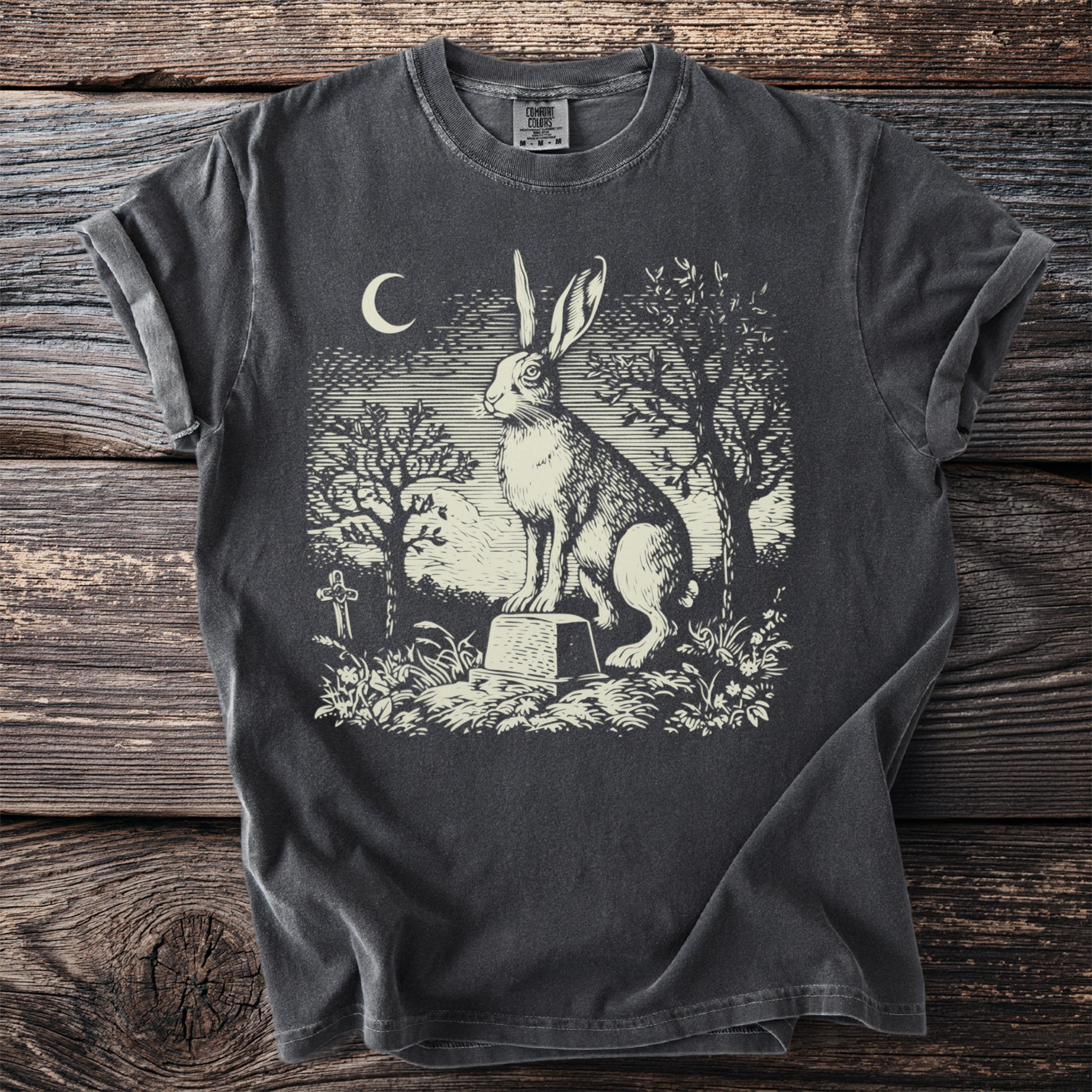 Dark t-shirt with vintage style graphic of a rabbit on a tombstone under a crescent moon.