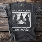 T-shirt with graphic of three witches playing cards and text "god forbid women have hobbies".