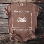 Brown t-shirt with white text "i do not wish to be perceived" and a frog illustration.