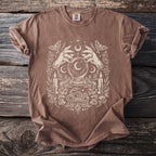Brown t-shirt with cream graphic featuring hands, crystal ball, moth, candles, crystals, and snake.