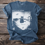 Blue t-shirt with a black cat, spider, moth, and bugs on a bed, text "you're not alone there are bugs".