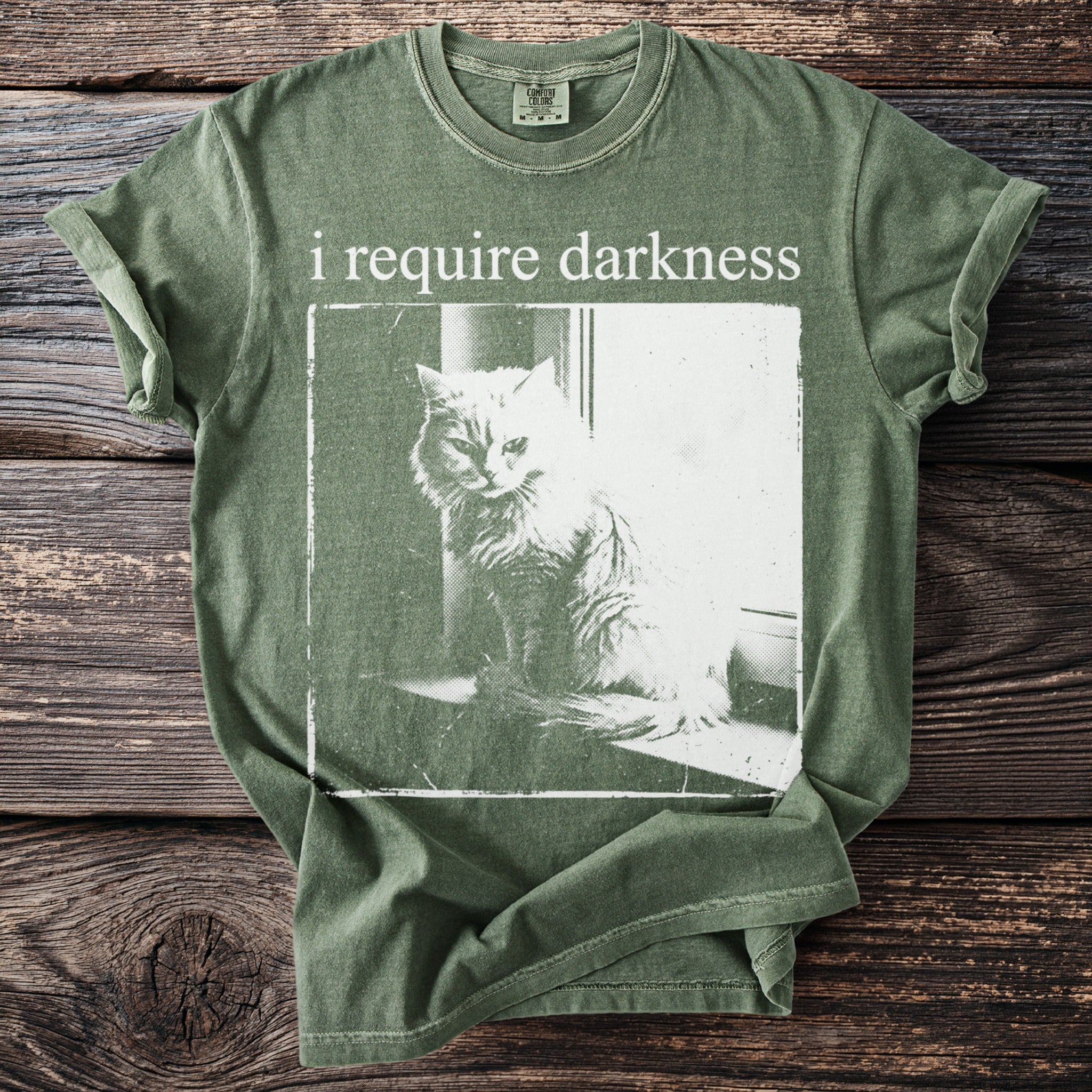 Green t-shirt with white graphic of a cat and text "i require darkness".